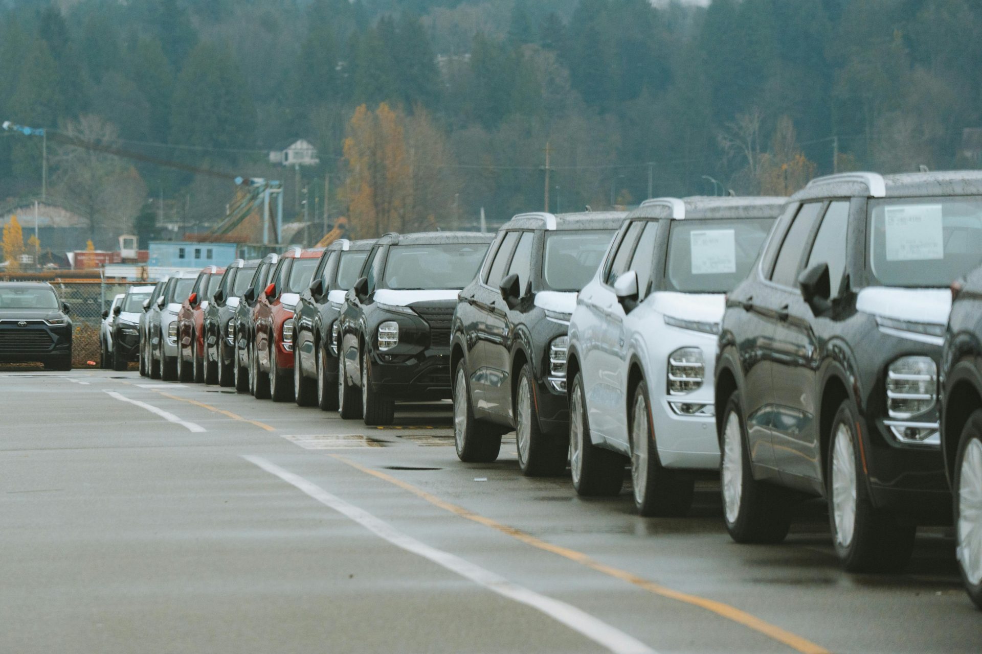Eine Reihe neuer SUVs steht auf dem Parkplatz eines Autohauses im Freien und wartet auf den Verkauf.