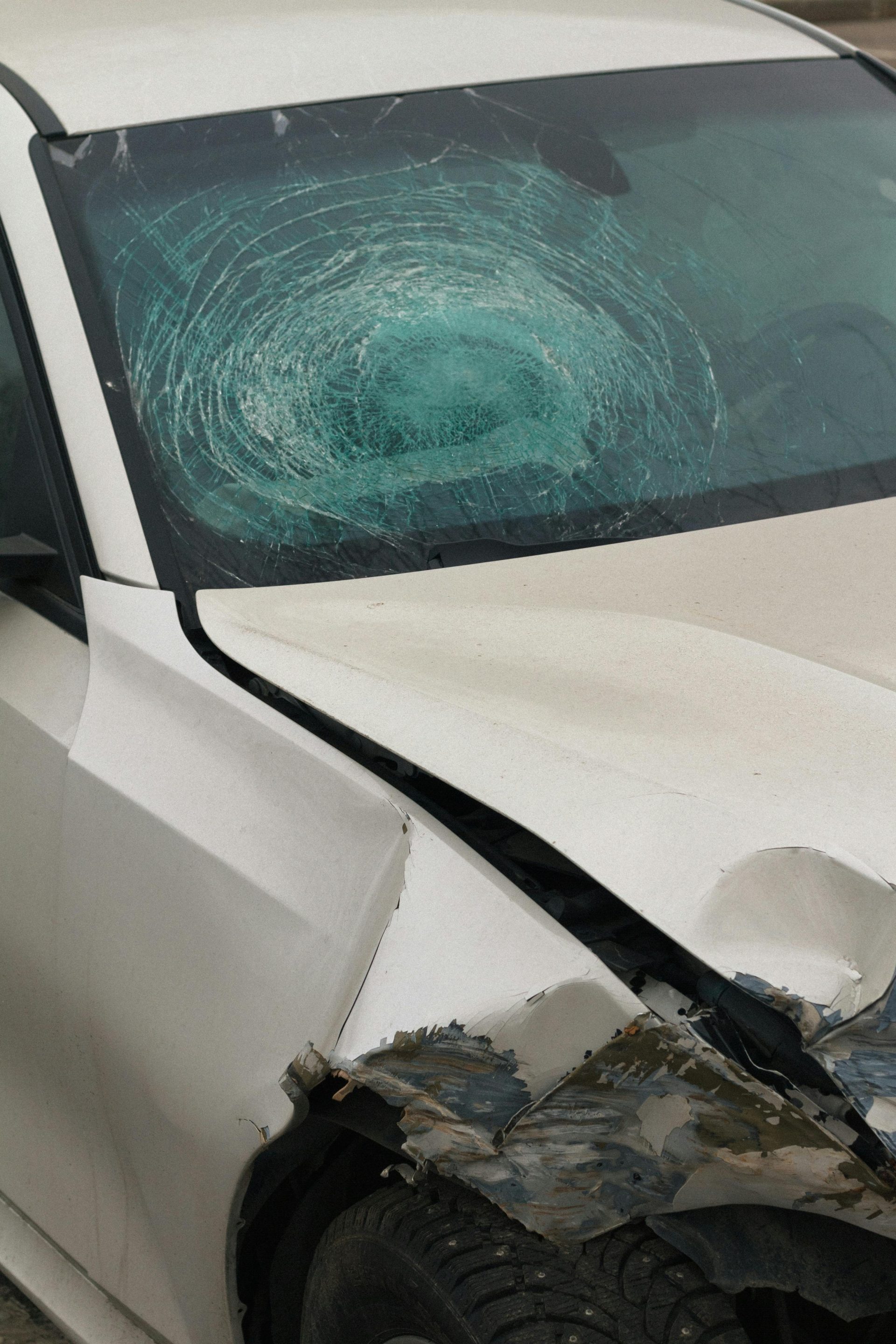 Detailansicht eines Autos mit zersplitterter Windschutzscheibe und Frontschaden, wobei die Unfalldetails hervorgehoben werden.